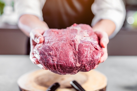 Chef in restaurant kitchen cooking,he is cutting meatの写真素材