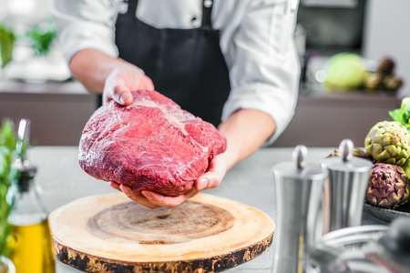 Chef in restaurant kitchen cooking,he is cutting meatの写真素材