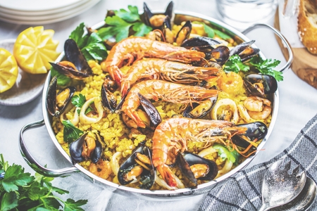 Traditional seafood paella in the pan on a wooden tableの写真素材