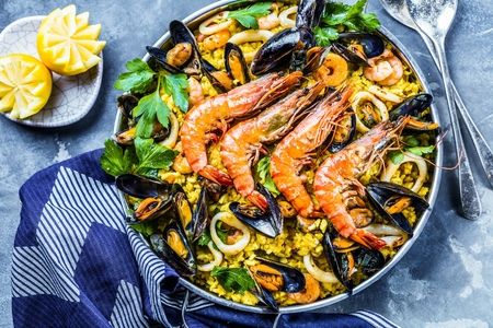 Traditional seafood paella in the pan on a wooden tableの写真素材