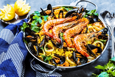 Traditional seafood paella in the pan on a wooden tableの写真素材