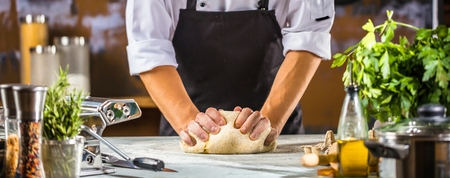 Male Chef cook preparing dough for pizza or Pasta on tableの写真素材