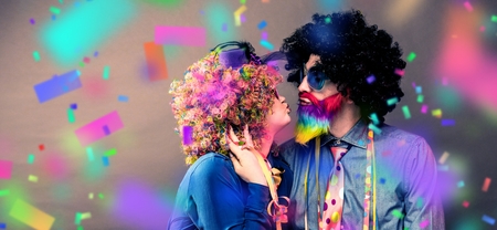 Portrait of party Men and woman in wig and glasses eating Carneval donutの写真素材