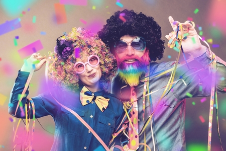 Portrait of party Men and woman in wig and glasses eating Carneval donutの写真素材
