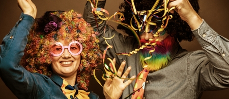 Portrait of party Men and woman in wig and glasses eating Carneval donutの写真素材