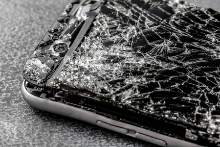 mobile phone with broken touchscreen on gray background.