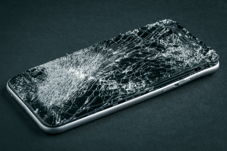 mobile phone with broken touchscreen on gray background.