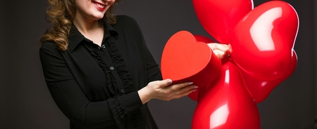 Beautiful young woman with heart shape air balloon on Black background.  Valentine's Dayの写真素材