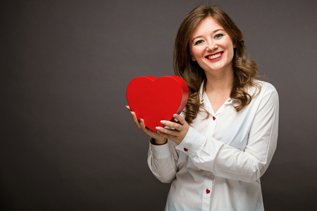 Beautiful young woman with heart shape air balloon on Black background.  Valentine's Dayの写真素材