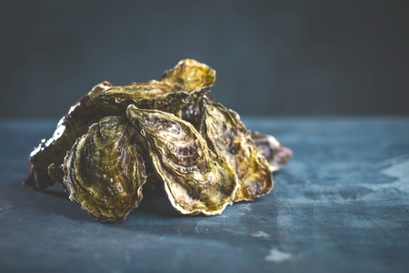 Fresh raw oysters on black old stone background with lemon