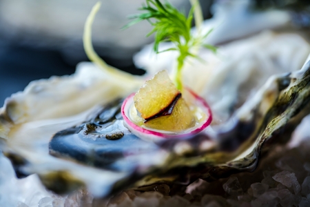 Fresh raw oysters on black old stone background with lemonの写真素材