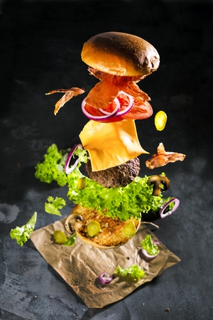 Big tasty home made burger with flying ingredients.の写真素材