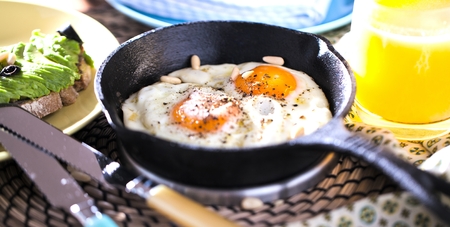 Fried egg. Close up view of the fried egg on a frying pan. Salted and spiced fried egg with parsley on cast iron pan and black backgroundの写真素材