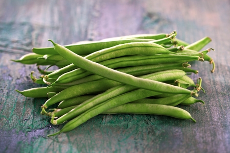 Green beans on wooden cutting board isolated on white vegetarian foodの写真素材