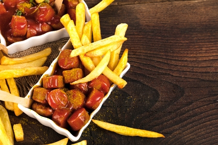 Traditional German currywurst, served with pommes on wooden background.の写真素材
