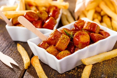 Traditional German currywurst, served with pommes on wooden background.の写真素材