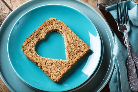 Slice of cereal toast bread with cut out heart shape.の写真素材