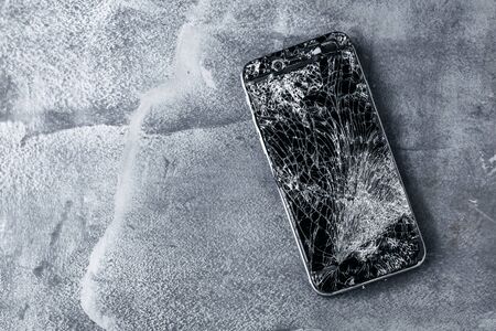 mobile phone with broken touchscreen on gray background.の写真素材