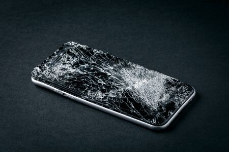 mobile phone with broken touchscreen on gray background.