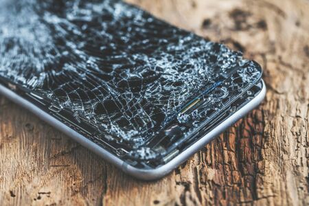 mobile phone with broken touchscreen on wooden background.の写真素材