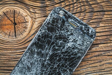 mobile phone with broken touchscreen on wooden background.の写真素材