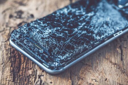 mobile phone with broken touchscreen on wooden background.の写真素材
