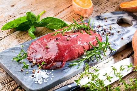 Fresh cow Liver on stone plate dekorated on wooden table with rosemary and Basilの写真素材