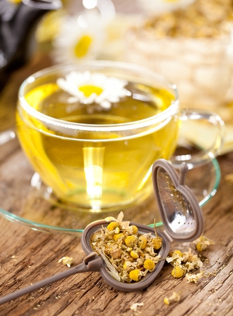 Cup of chamomile tea with chamomile flowers on wooden background.の写真素材