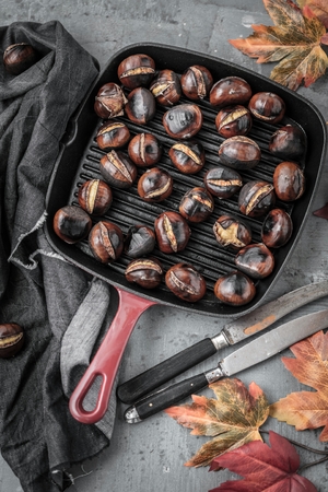Roasted chestnuts served in chestnut pan on an old tableの写真素材