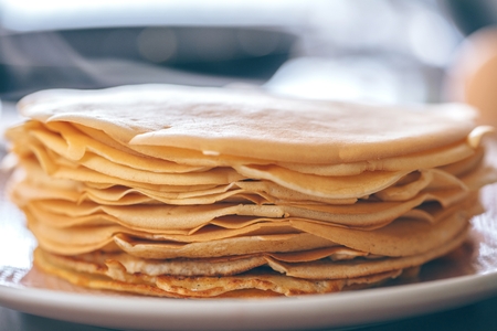 Woman making thin pancakes on frying pan in kitchenの写真素材