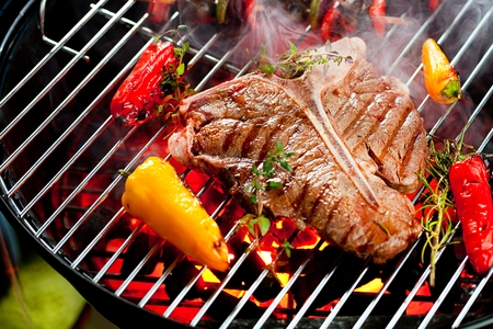 Beef T-bone steaks on the grill with flamesの写真素材