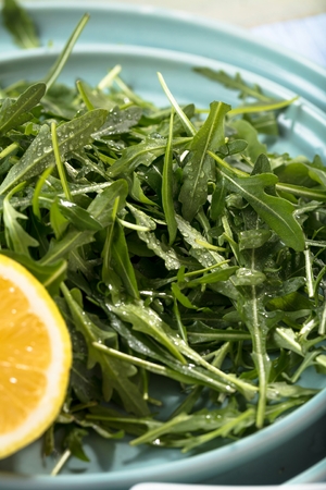 Fresh arugula leaves on wooden bowl, rucola. Arugula rucola on wooden old background.の写真素材