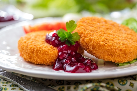 Breaded and baked camembert with cranberry sauce on wooden tabelの写真素材