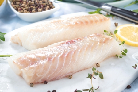 Fresh fish, raw cod fillets with addition of herbs and lemonの写真素材