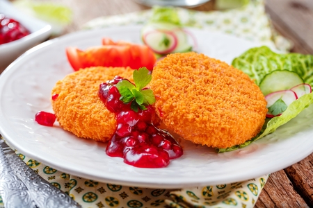 Breaded and baked camembert with cranberry sauce on wooden tabelの写真素材