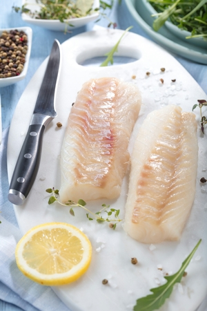 Fresh fish, raw cod fillets with addition of herbs and lemonの写真素材