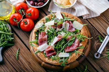 Fresh Rucola Pizza with parma ham on wooden cuting boardの写真素材