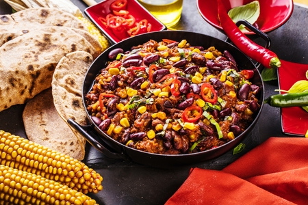 Chili con carne in a clay bowl on a concrete or stone rustic background- traditional dish of mexican cuisine.Top viewの写真素材