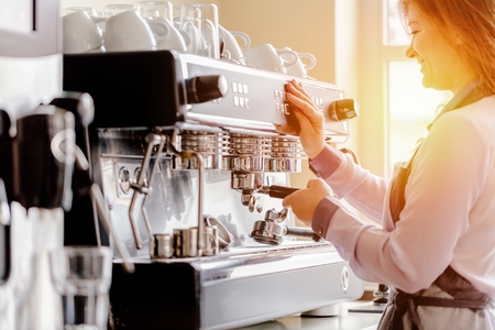 Women Barista using coffee machine for making coffee in the cafeの写真素材