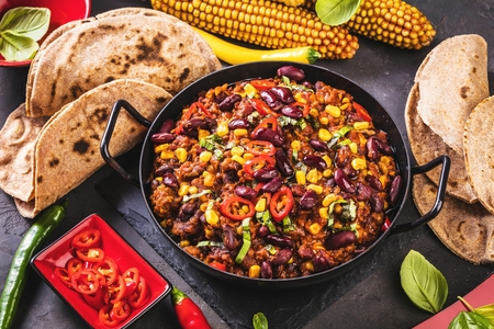 Chili con carne in a clay bowl on a concrete or stone rustic background- traditional dish of mexican cuisine.Top viewの写真素材
