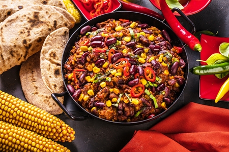 Chili con carne in a clay bowl on a concrete or stone rustic background- traditional dish of mexican cuisine.Top viewの写真素材