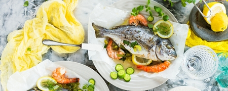 delicious roasted dorado or sea bream fish with lemon and fresh Prawns , fresh parsley and spinach on white platterの写真素材