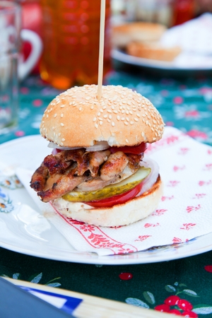 Tasty grilled chicken burger with lettuce and mayonnaise served on on a rustic wooden plate on table.の写真素材