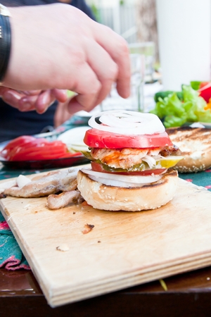 Tasty grilled chicken burger with lettuce and mayonnaise served on on a rustic wooden plate on table.の写真素材