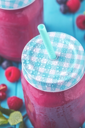 Flat-lay of colorful smoothies in bottles with fresh tropical fruit and superfoods on concrete background.の写真素材
