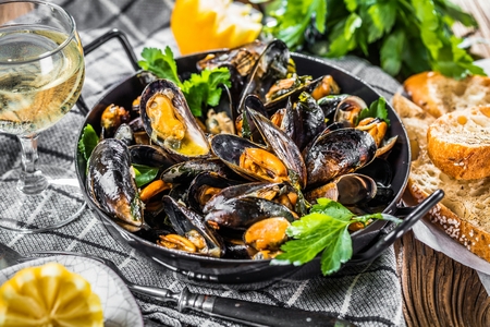 Steamed mussels in white wine sauce on dark Tableの写真素材
