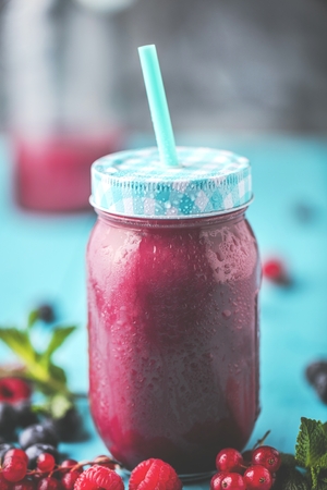 Flat-lay of colorful smoothies in bottles with fresh tropical fruit and superfoods on concrete background.の写真素材