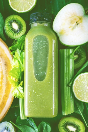 Flat-lay of colorful smoothies in bottles with fresh tropical fruit and superfoods on concrete background.の写真素材