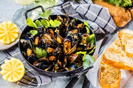 Steamed mussels in white wine sauce on dark Table