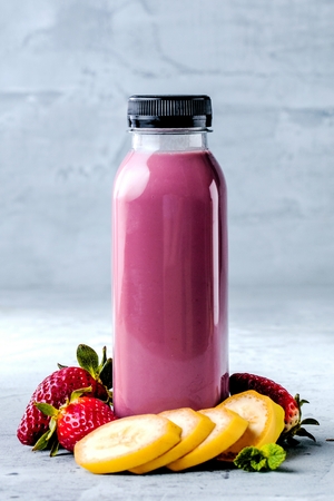 Flat-lay of colorful smoothies in bottles with fresh tropical fruit and superfoods on concrete background.の写真素材